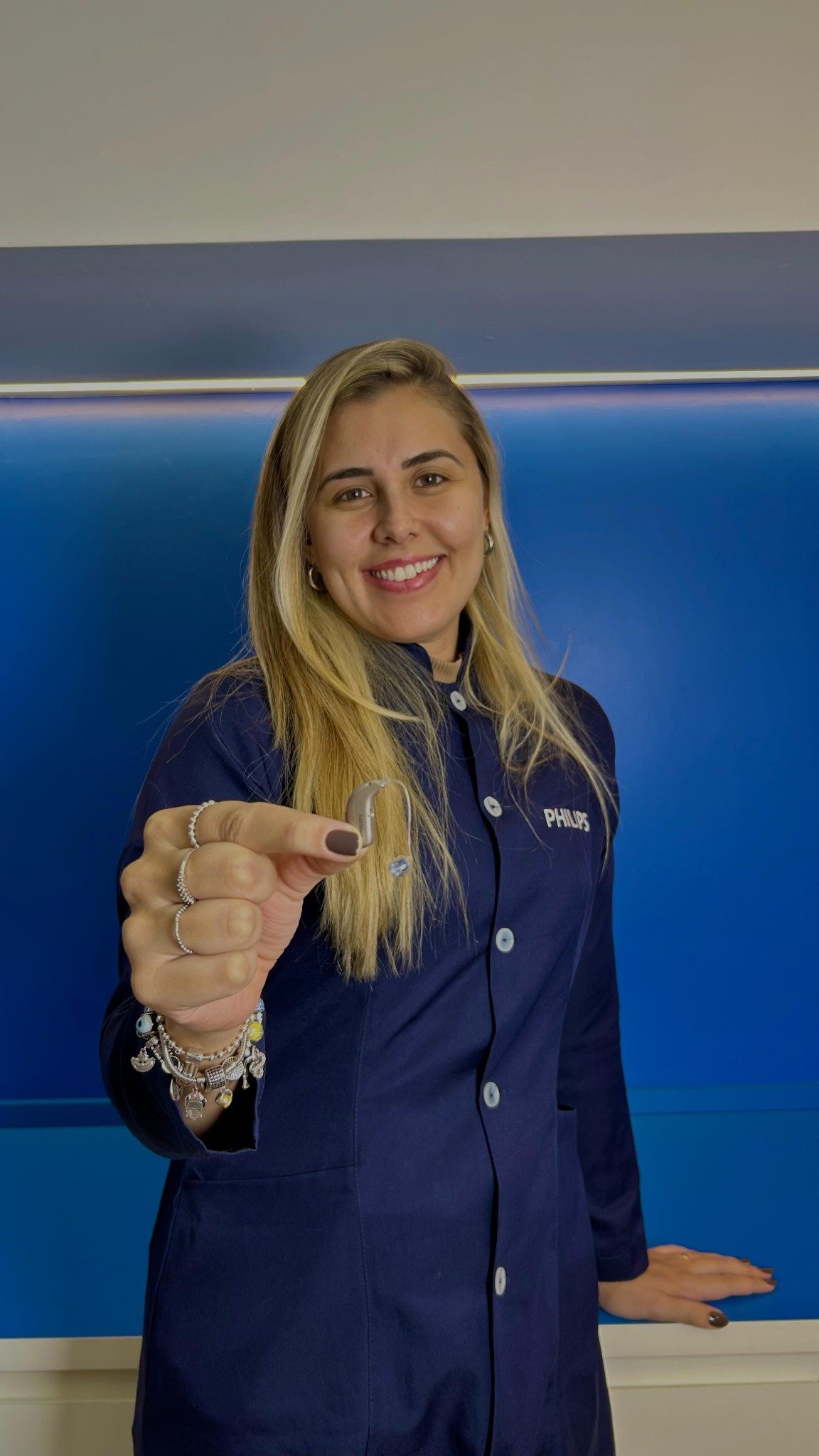 Profissional da equipe PH apresentando um aparelho auditivo